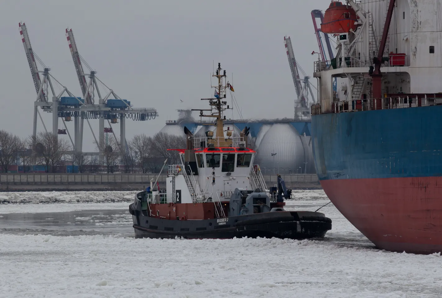 Der Schlepper „Bugsier 2“ manövriert ein Schiff durch eine Eisschicht im Hamburger Hafen