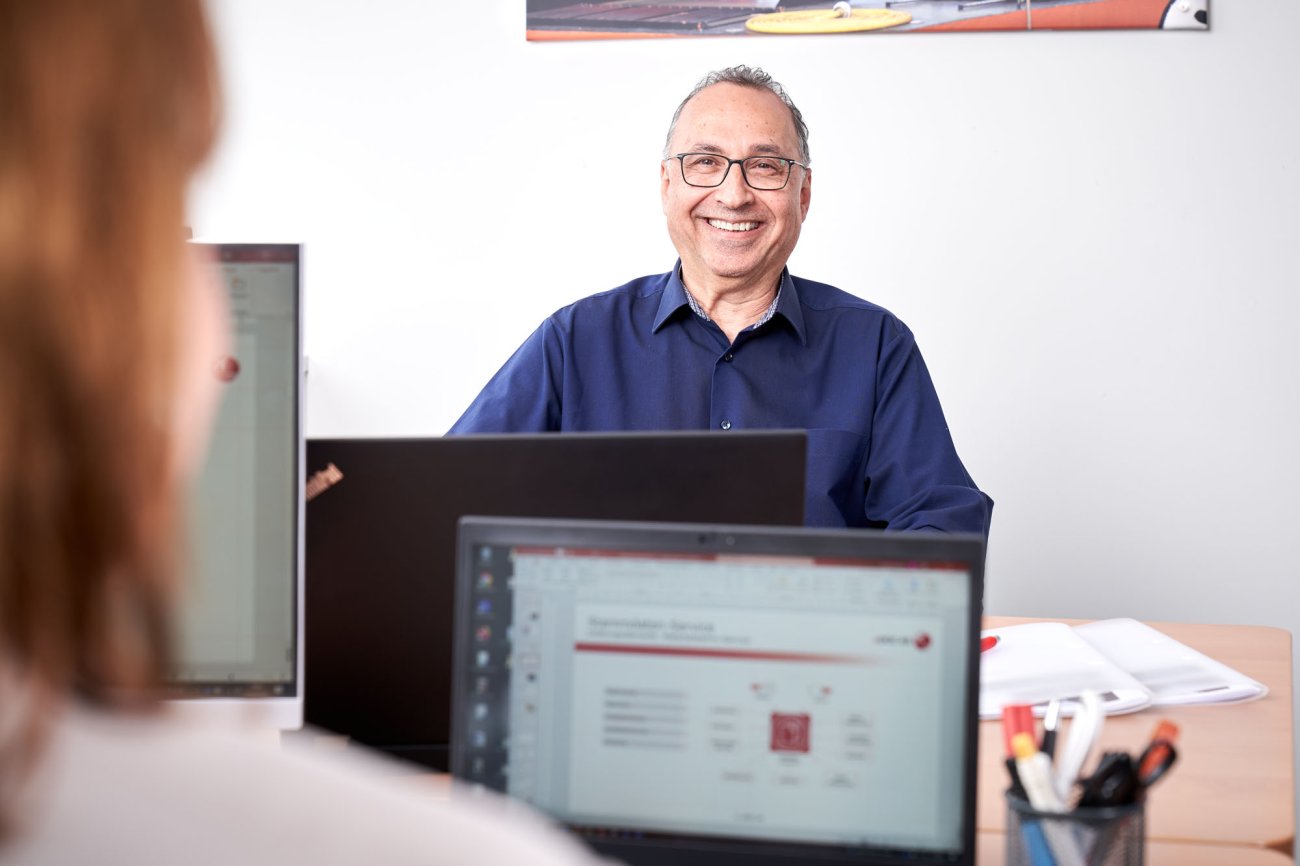 Ein lächelnder Mitarbeiter an seinem Büro-Arbeitsplatz