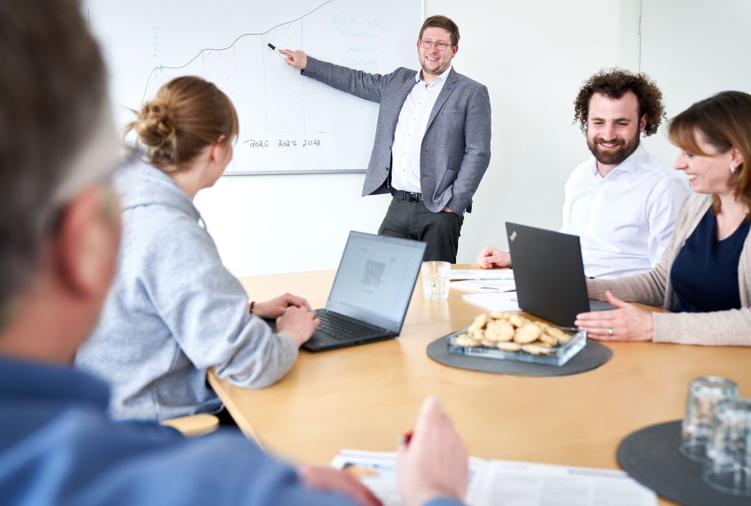 Ein Mitarbeiter hält eine Präsentation am Whiteboard vor Kollegen
